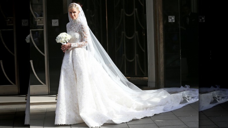 Nicky Hilton sosteniendo un ramo el día de su boda con un vestido de gala con una cola larga.