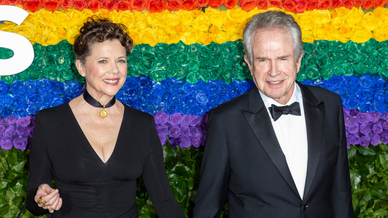 Annette Bening y Warren Beatty frente a una pared de flores de arcoíris