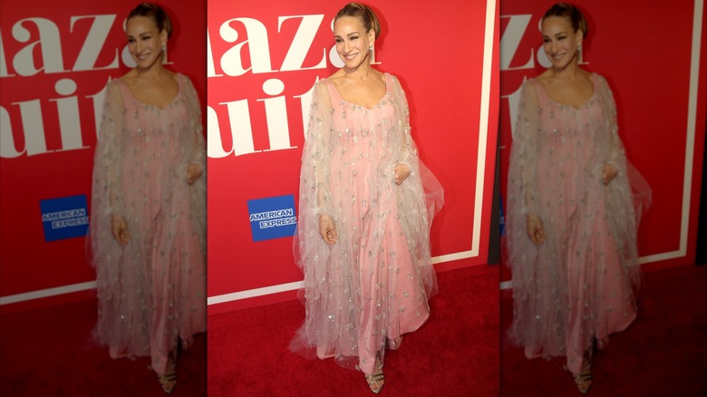 Sarah Jessica Parker sonriendo en un evento de alfombra roja con un vestido rosa fluido en 2022.