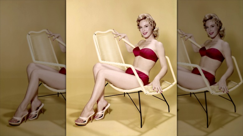 Barbara Eden sentada en una silla con bikini rojo y tacones blancos