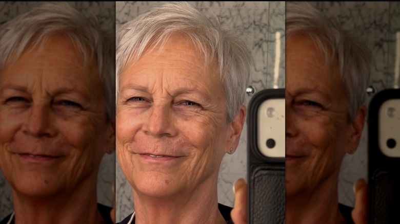 Jamie Lee Curtis sonriendo en una selfie en el espejo sin maquillaje.