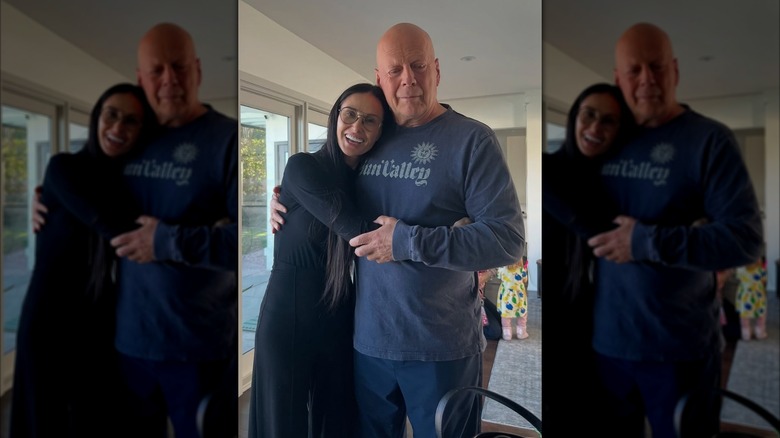Demi Moore con gafas y un conjunto negro abrazando a Bruce Willis con una sudadera azul.