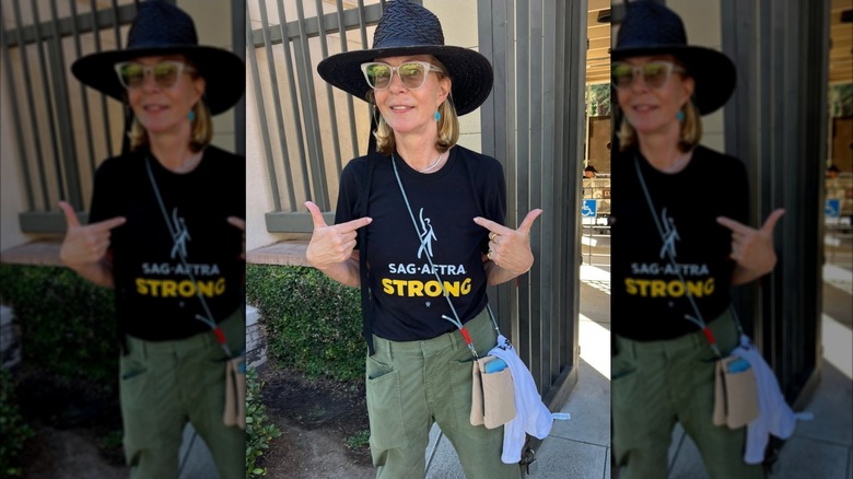 Allison Janney posando en una foto sincera apuntando a su camisa SAG-AFTRA mientras usa gafas de sol y un sombrero negro.