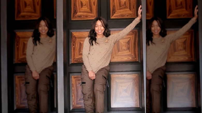 Angela Bassett posa con un traje marrón con la mano en la pared.