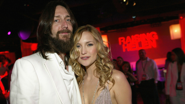 Kate Hudson sonriendo con el pelo suelto junto a Chris Robinson.