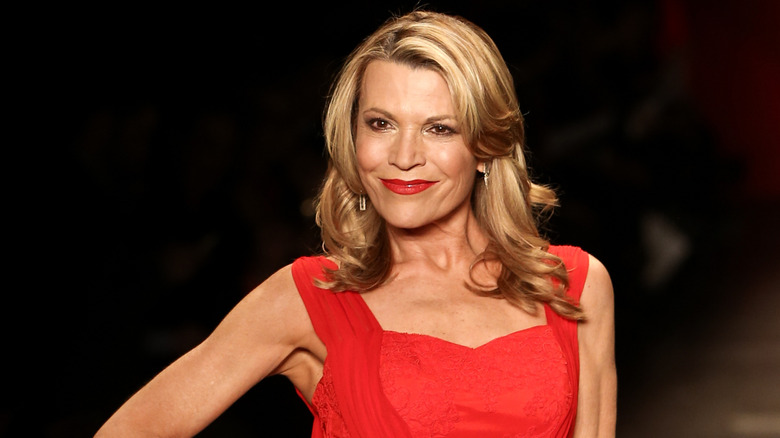 Vanna White con un vestido rojo con lápiz labial rojo sobre un fondo negro.