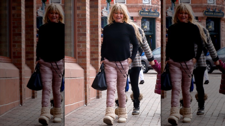 Goldie Hawn camina con pantalones para la nieve rosas acolchados y un suéter negro