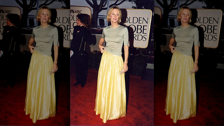 Meg Ryan posando en la alfombra roja luciendo una falda de raso amarilla.