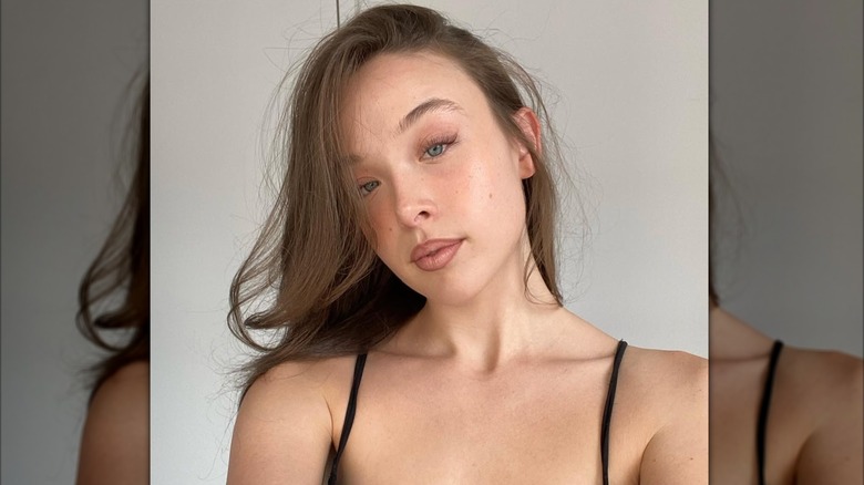Ella Beatty tomándose una selfie, vistiendo un top negro con un mínimo de maquillaje