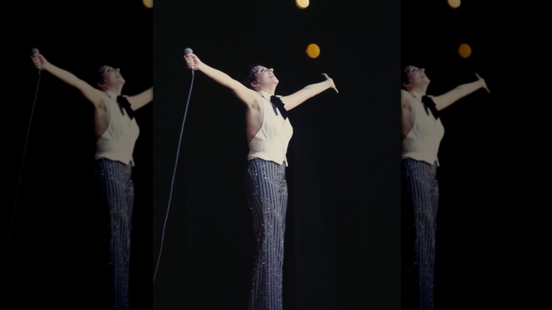 Liza Minnelli actuando en el escenario con un micrófono en la mano y las manos en el aire.