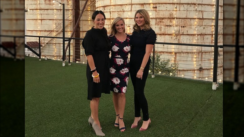 Joanna Gaines vestida de negro sonriendo junto a Reese Witherspoon con un vestido floral y Jenna Bush Hager vestida completamente de negro.