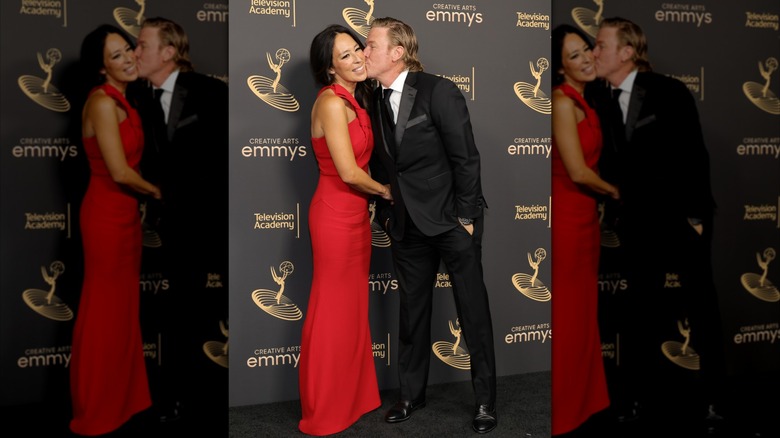 Chip Gaines con traje y besando a su esposa Joanna Gaines con un vestido rojo en un evento de alfombra roja.