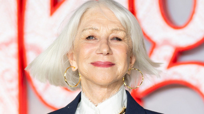 Helen Mirren posando en la alfombra roja con unos aros dorados.