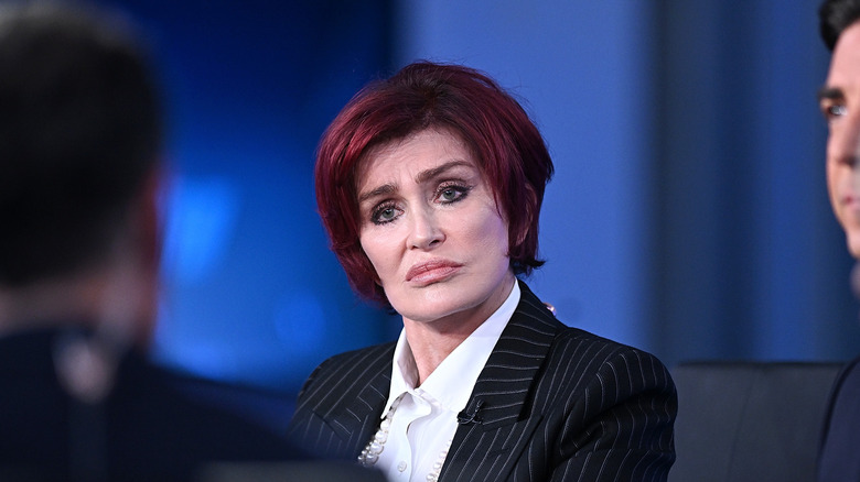 Sharon Osbourne se sienta en un escritorio durante una entrevista en un panel