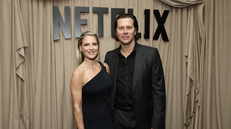 Ali Larter y Hayes MacArthur vestidos con un vestido y traje negros en un evento de Netflix.