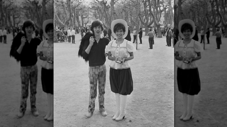 Mick Jagger con pantalones de madrás y una camiseta polo posando con su esposa Bianca Jagger con un atuendo antiguo.