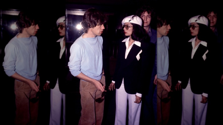 Mick Jagger con una sudadera azul y pantalones de pana fotografiados junto a su esposa Bianca Jagger con una chaqueta negra y una gorra blanca.