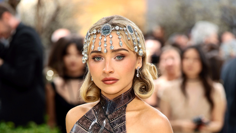 Sabrina Carpenter posando en la Met Gala 2026 con un tocado adornado y un top sin mangas de tiras de película.