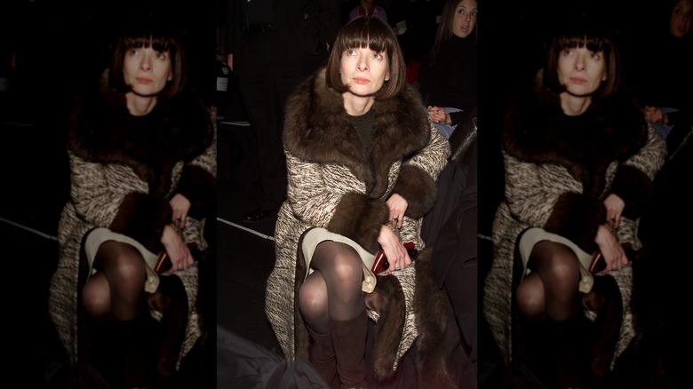 Anna Wintour mira hacia arriba con cabello castaño oscuro y una chaqueta con adornos de piel.