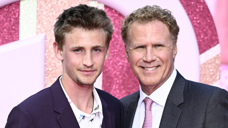 Will Ferrell posando con su hijo Magnus en un evento de alfombra roja con un fondo rosa brillante.