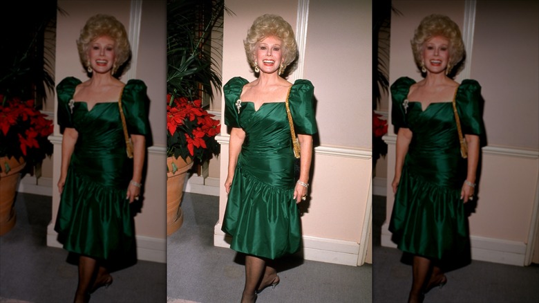 Eva Gabor sonríe luciendo un vestido verde esmeralda y una melena voluminosa.