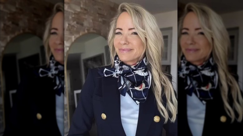 Una mujer con cabello largo con mechones que enmarcan el rostro y vestida con una chaqueta y una bufanda.