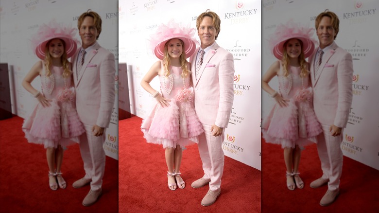 Dannielynn Birkhead está junto a Larry Birkhead con un vestido rosa y un sombrero.