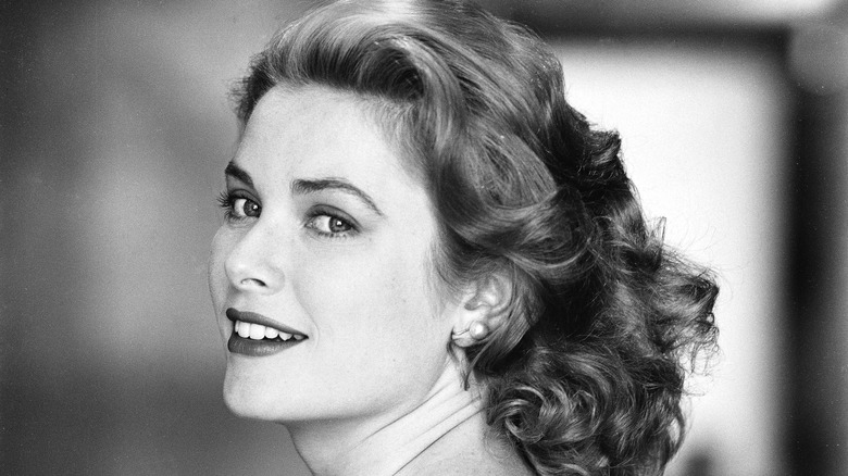 Foto en blanco y negro de Grace Kelly con el pelo suelto y el rostro ligeramente vuelto hacia la cámara, sonriendo.