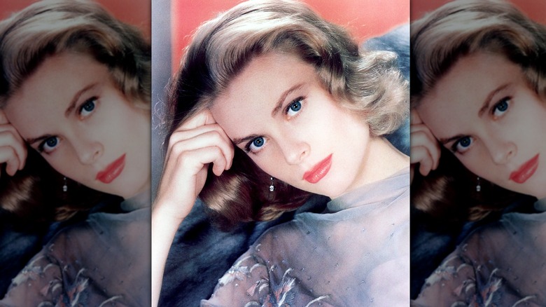 Grace Kelly posa con la cabeza apoyada en la mano, luciendo un top gris, maquillaje sencillo y cabello suave.