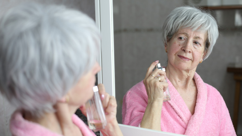 Mujer mayor usando perfume en el baño