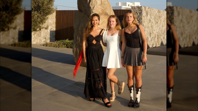 Jessica Alba posando afuera con un vestido negro con sus hijas Honor y Haven.