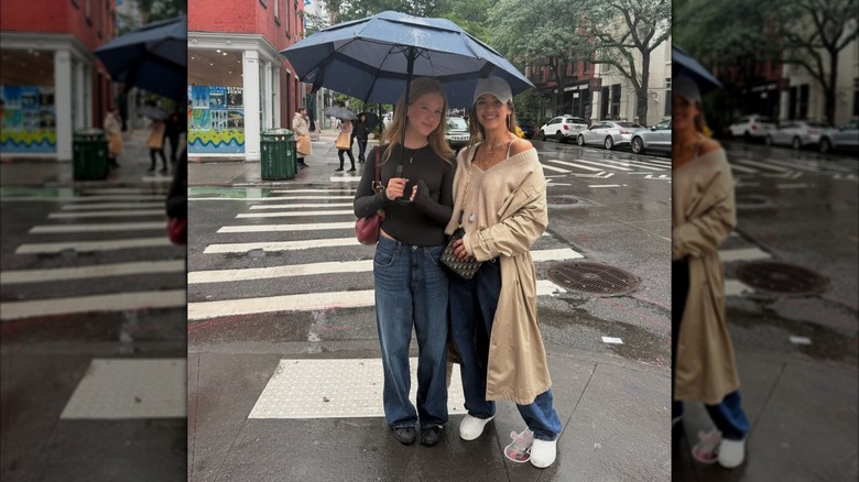 Jessica Alba posando afuera bajo la lluvia con su hija Haven sosteniendo un paraguas.