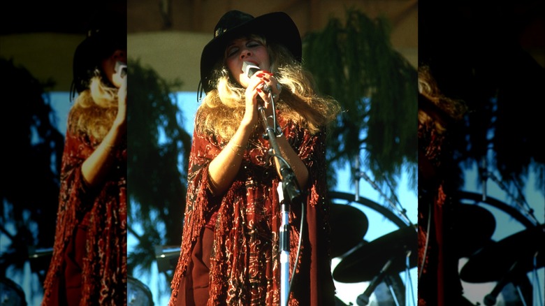 Stevie Nicks con un sombrero negro y un traje rojo actuando con Fleetwood Mac en 1977.