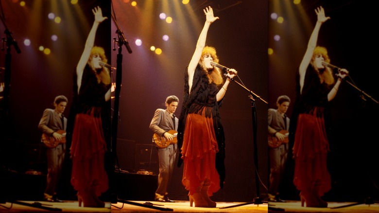 Stevie Nicks en el escenario con la mano en el aire con una falda roja y un top negro actuando con Fleetwood Mac en 1979.