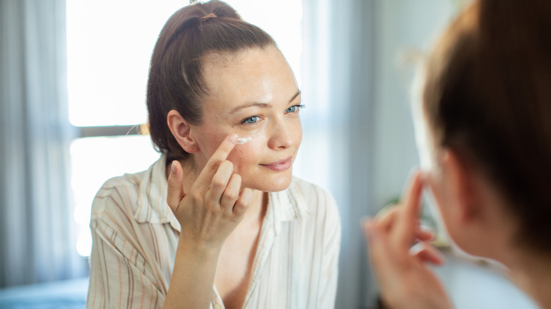 Una mujer aplicándose una crema hidratante en la cara.