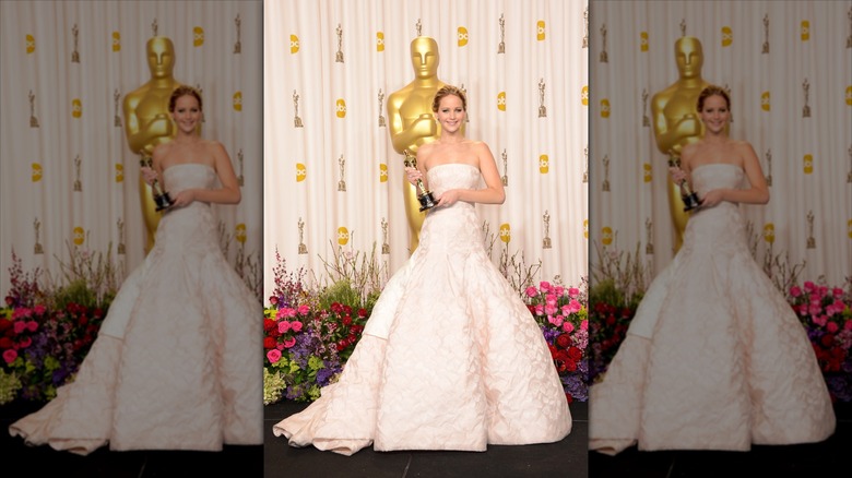 Jennifer Lawrence sostiene un premio Oscar con un vestido de gala blanco