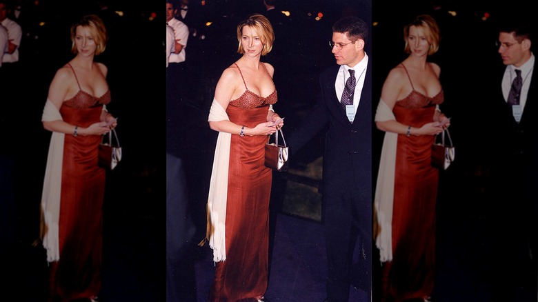 Lisa Kudrow posando en un evento de alfombra roja con un vestido rojo con pañuelo blanco y pelo corto.