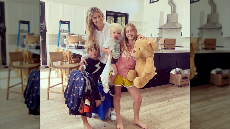 Christina Haack, Taylor, Brayden y Hudson posan juntas con un osito de peluche en una cocina con cajas de mudanza.