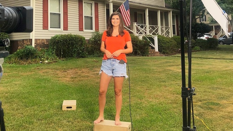 Kaitlan Collins se para frente a la casa de su hermana y sonríe (agosto de 2019)