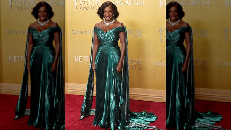Viola Davis posando en la alfombra roja con un brillante vestido verde esmeralda con hombros descubiertos, detalles plisados ​​y cola.