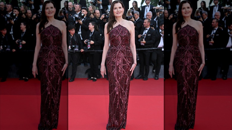 Geena Davis posando en la alfombra roja con un vestido sin tirantes de color rojo vino con intrincados diseños de lentejuelas.