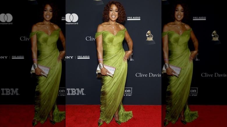 Gayle King posando en la alfombra roja con la mano en la cadera y un vestido chartreuse con hombros descubiertos.