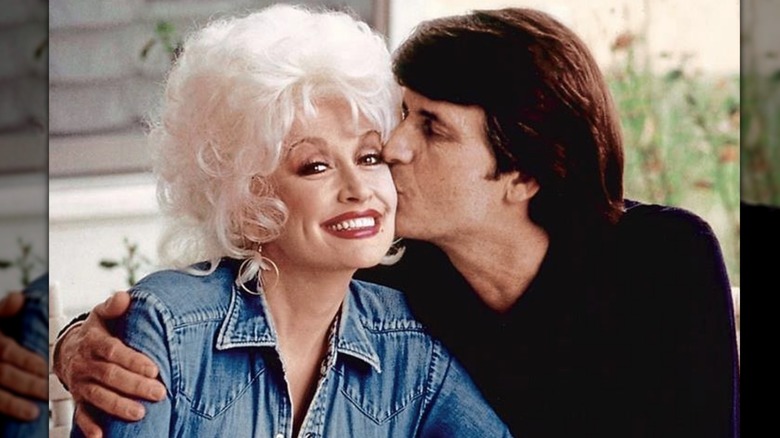 Dolly Parton sonríe mientras su marido Carl Dean le planta un beso en la mejilla