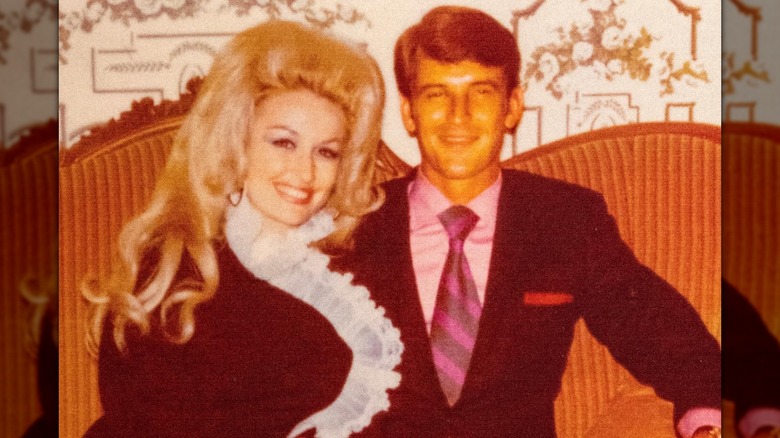 Dolly Parton y su esposo Carl Dean posan juntos sentados en un sofá naranja retro