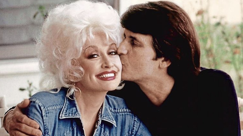 Dolly Parton con una chaqueta vaquera recibiendo un beso en la mejilla de su difunto marido Carl Dean.