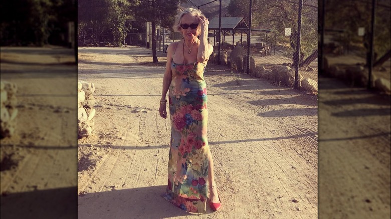 Tippi Hedren es fotografiada en un camino de tierra con un vestido floral hasta el suelo y zapatos rojos.