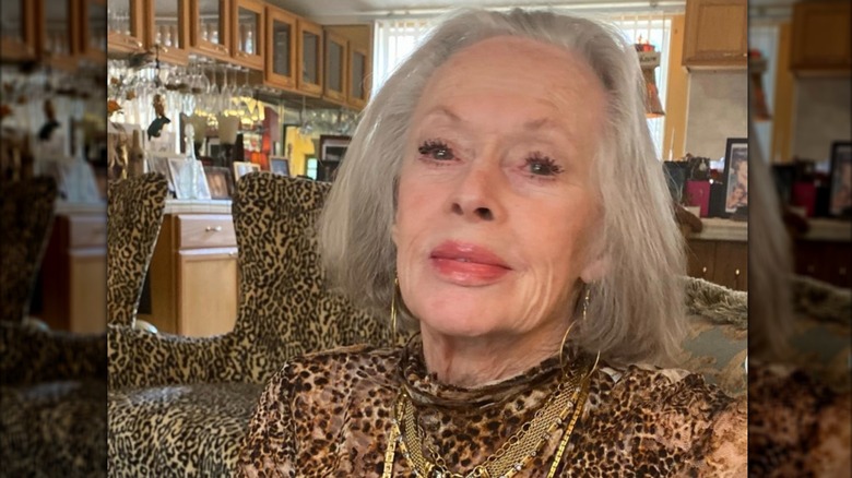 Tippi Hedren es fotografiada con un vestido con estampado animal mientras está sentada en una habitación con sillas con estampado animal al fondo.