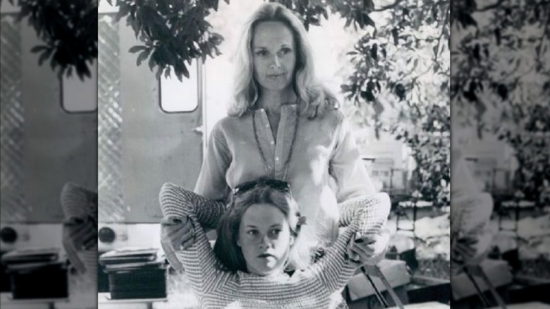 Una fotografía en blanco y negro muestra a una joven Melanie Griffith sentada en una silla mientras su madre Tippi Hedren la abraza por detrás.