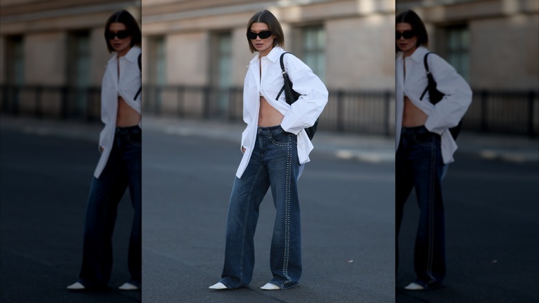 Una mujer con camisa blanca, jeans y tacones blancos en punta.