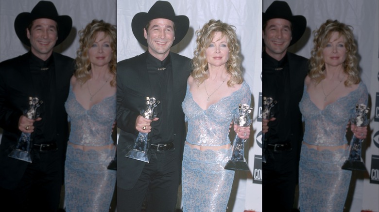 Clint Black con un traje completamente negro y Lisa Hartman Black con un conjunto de dos piezas azul brillante en los Premios ACM 2000.